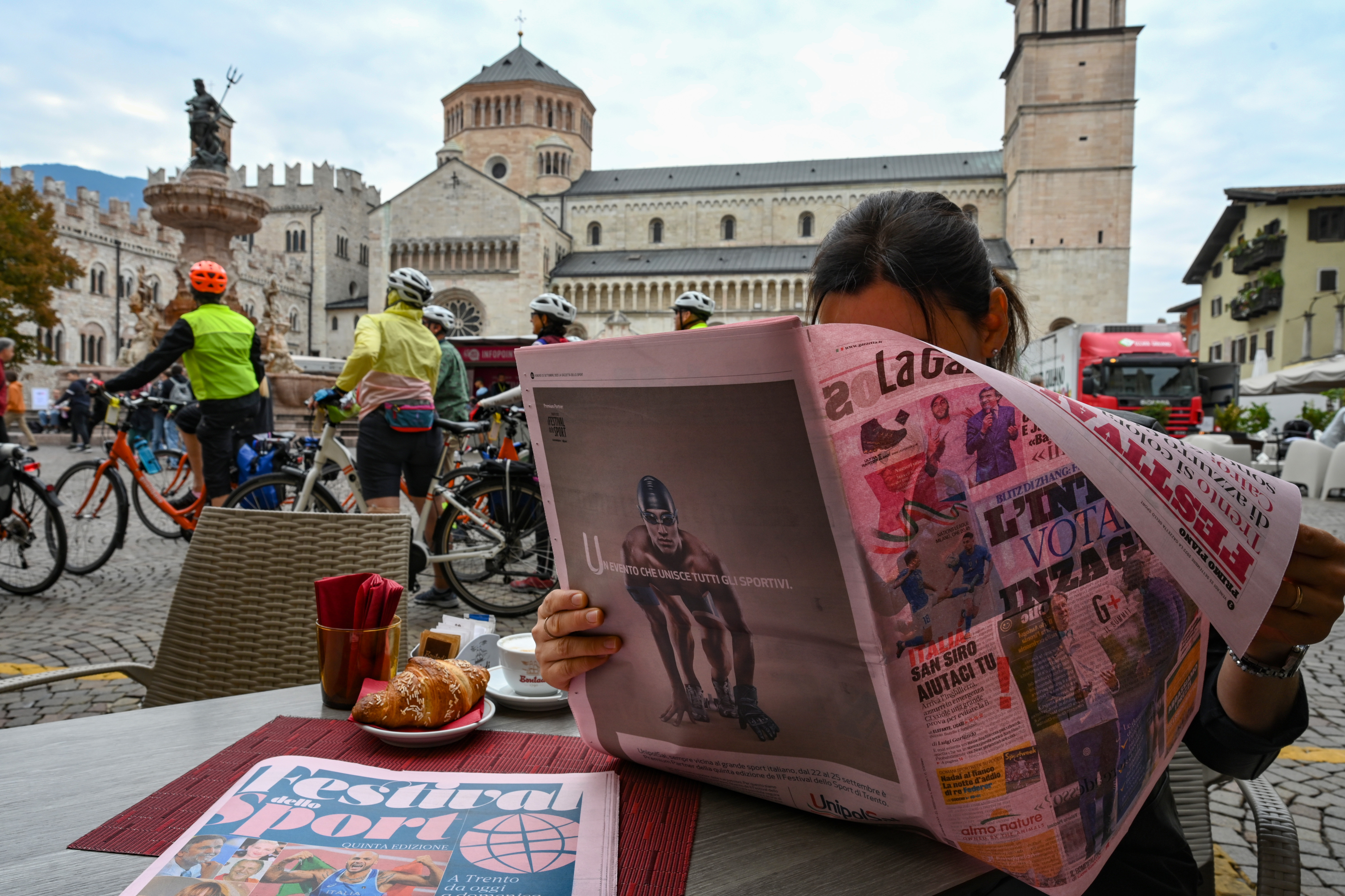 COLORE Nella foto: persona con Gazzetta, ciclisti, fontana e Duomo sullo sfondo Festival dello Sport Piazza Duomo Trento, 23 settembre 2022