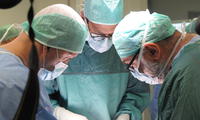 Equipe di medici durante un intervento chirurgico in sala operatoria per ricostruire la parete addominale con muscoli della gamba 
